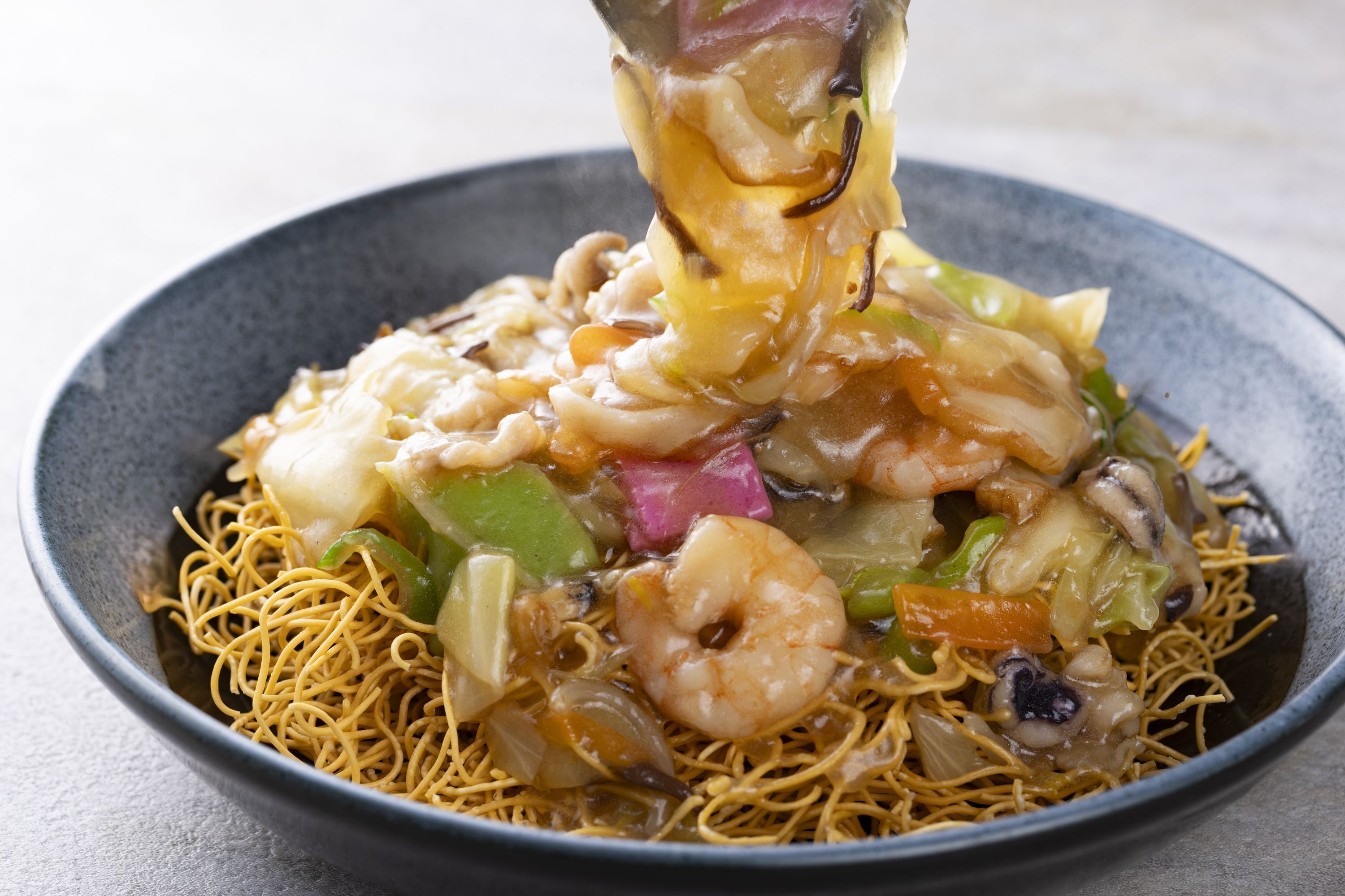 A bowl of noodles with shrimp and vegetables.