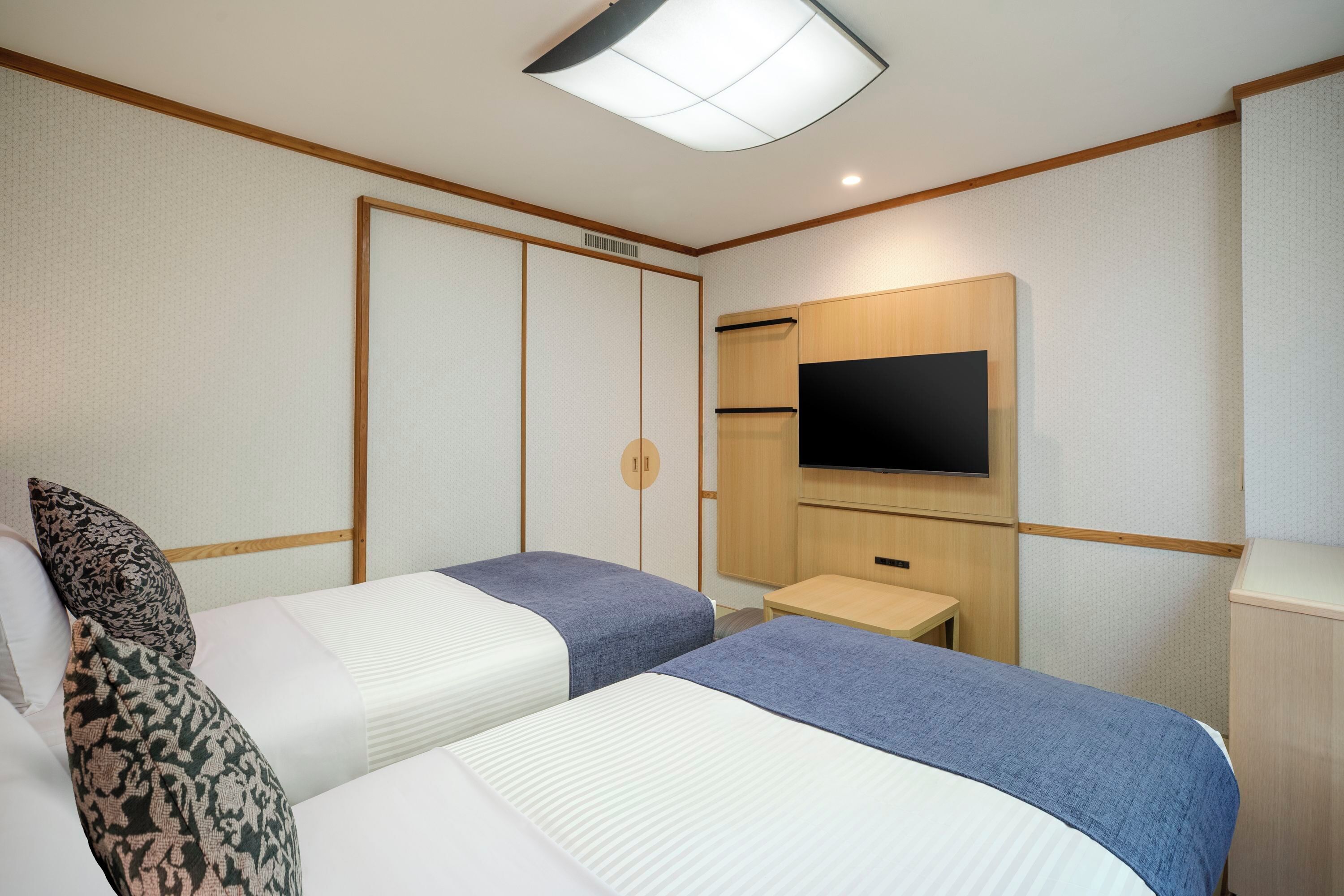 Une chambre d’hôtel avec deux lits, une télévision, une petite table et une armoire.