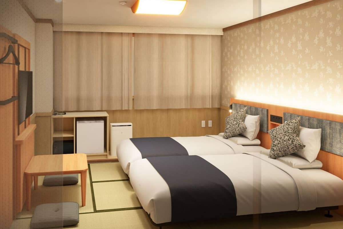 Una habitación de hotel con dos camas, un escritorio, una silla y una mesita.