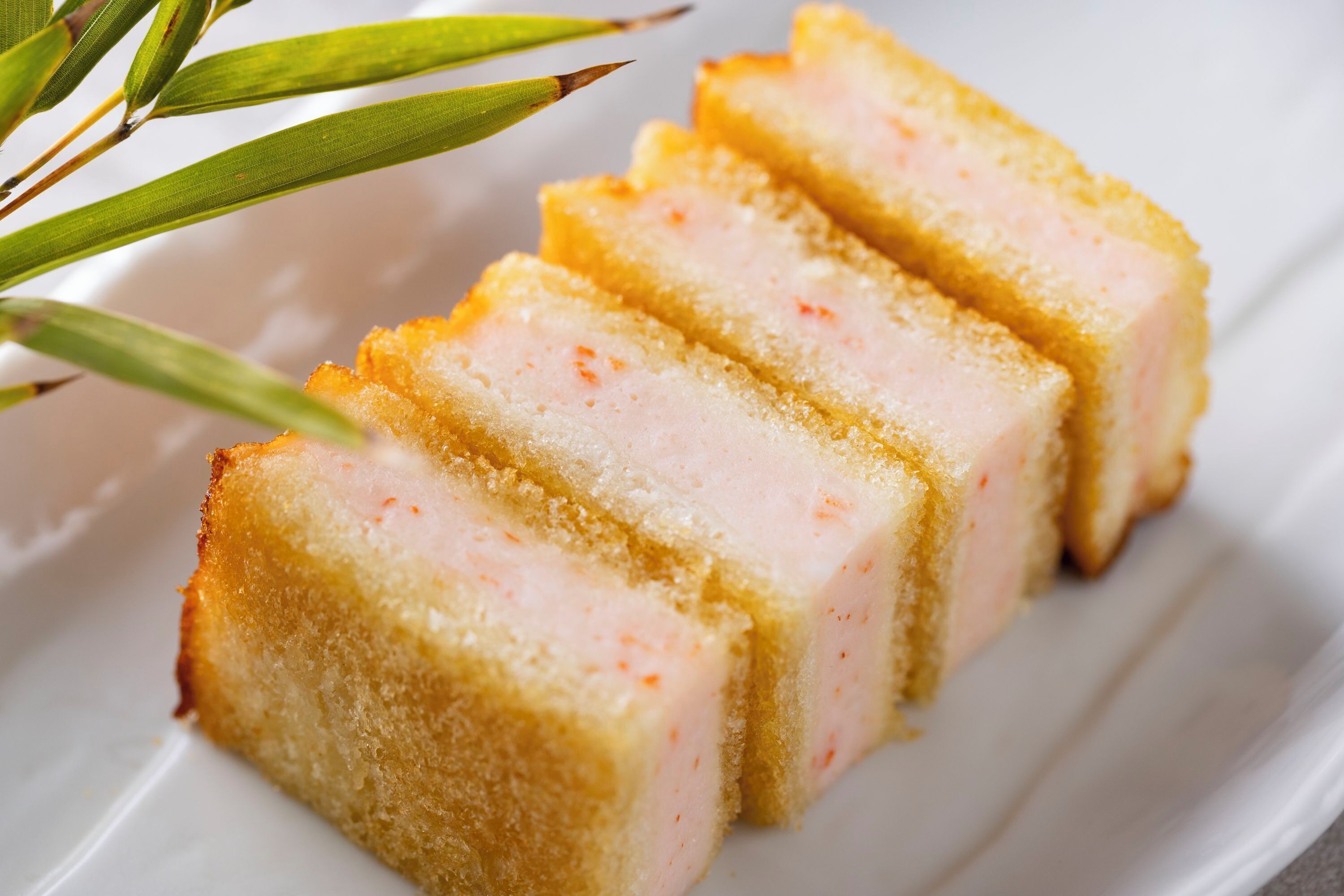 A white plate with four slices of breaded meat.