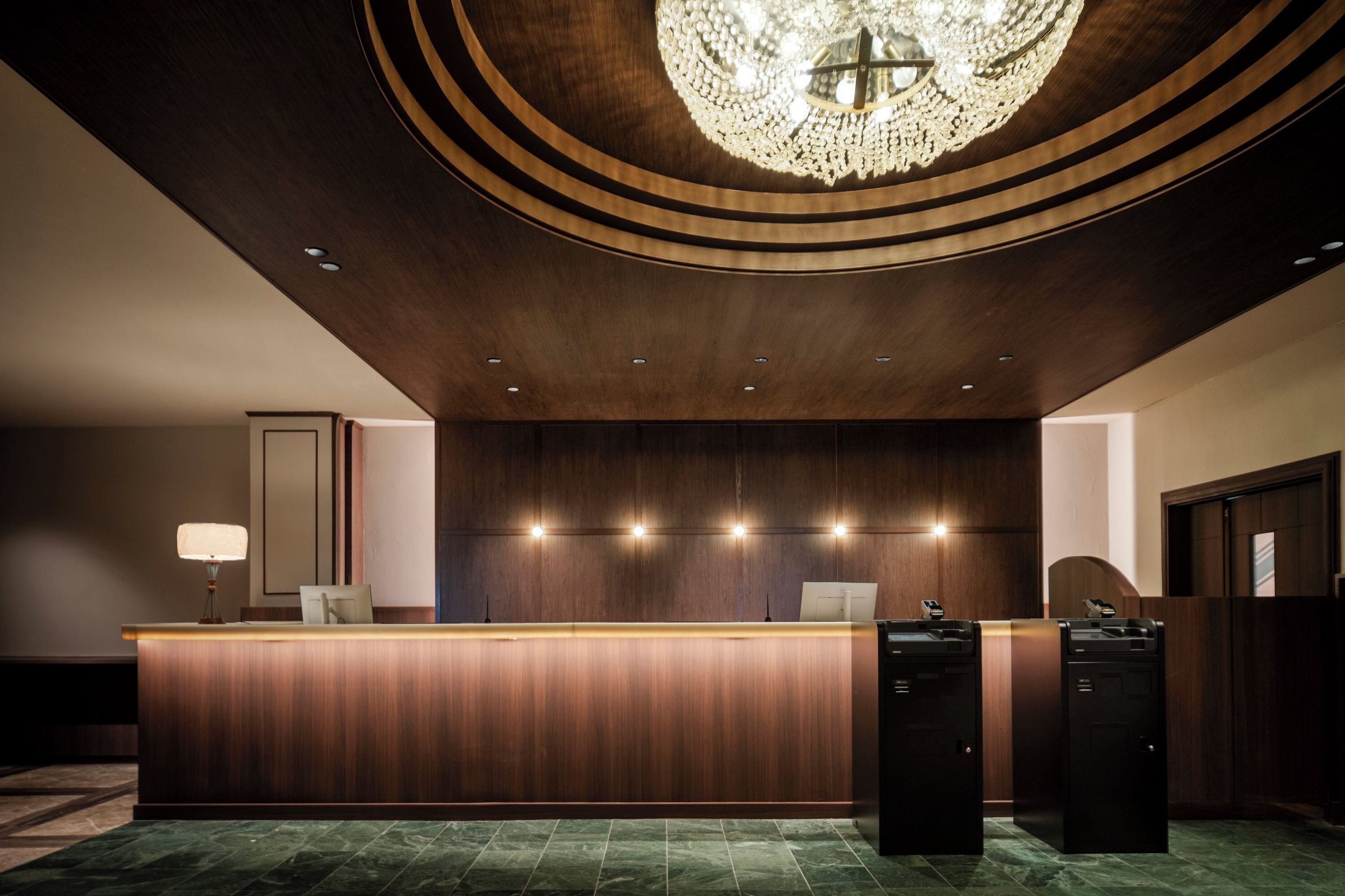 Ein Empfangsbereich mit Holztresen, einer Chandelierleuchtre und einem modernen Design.