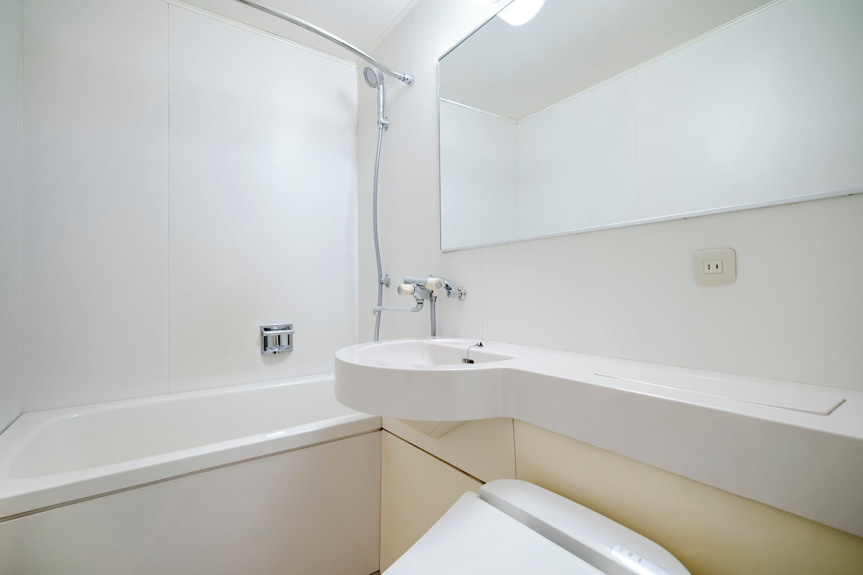 A bathroom with a bathtub, a sink, a mirror, and a showerhead.