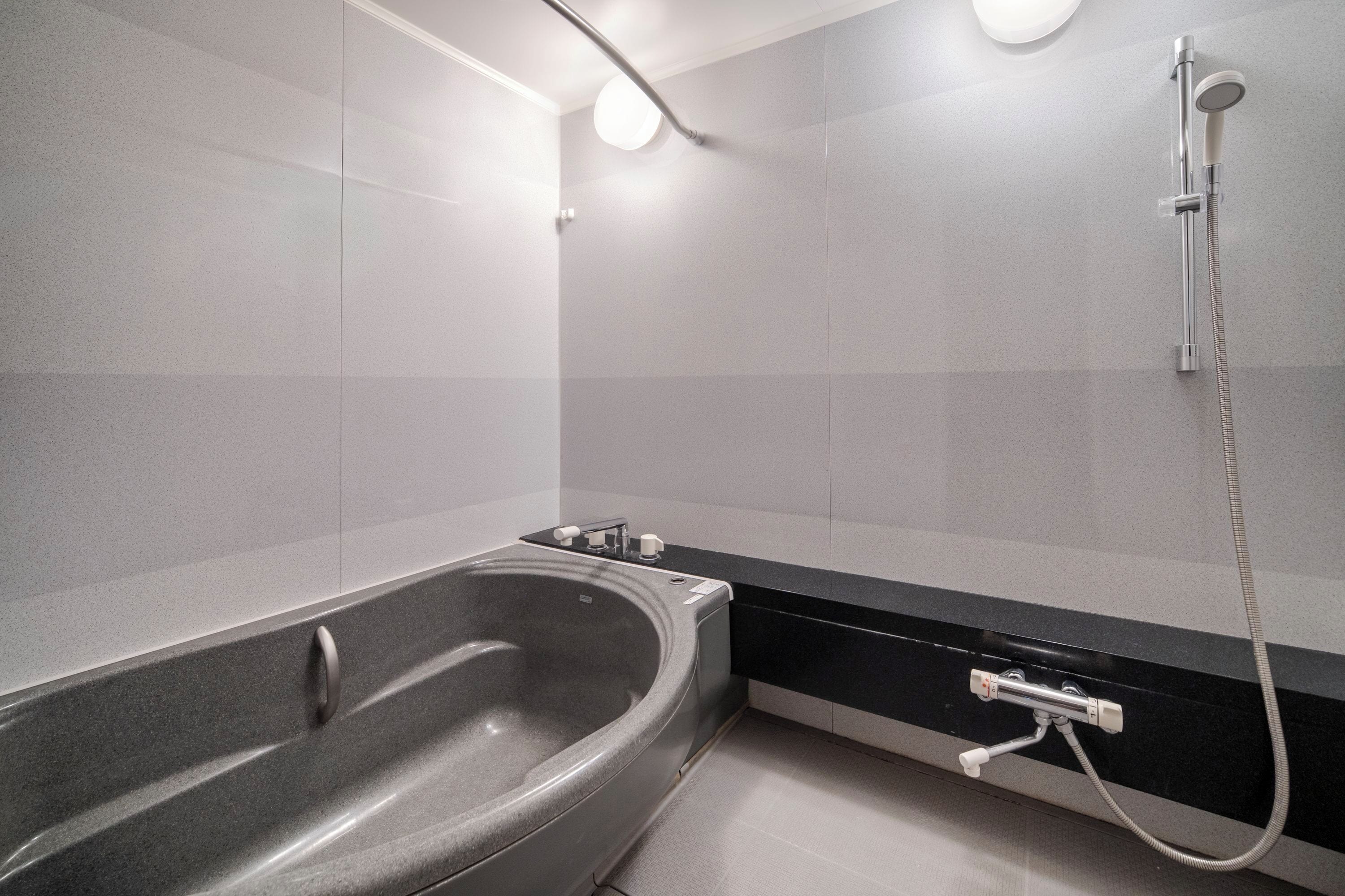Een moderne badkamer met een vrijstaand bad, een douchekop en een handdoekrek.