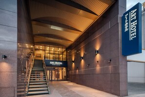 De ingang van The Art Hotel met een trap naar de deuren, een modern architectonisch ontwerp en een naamplaatje.