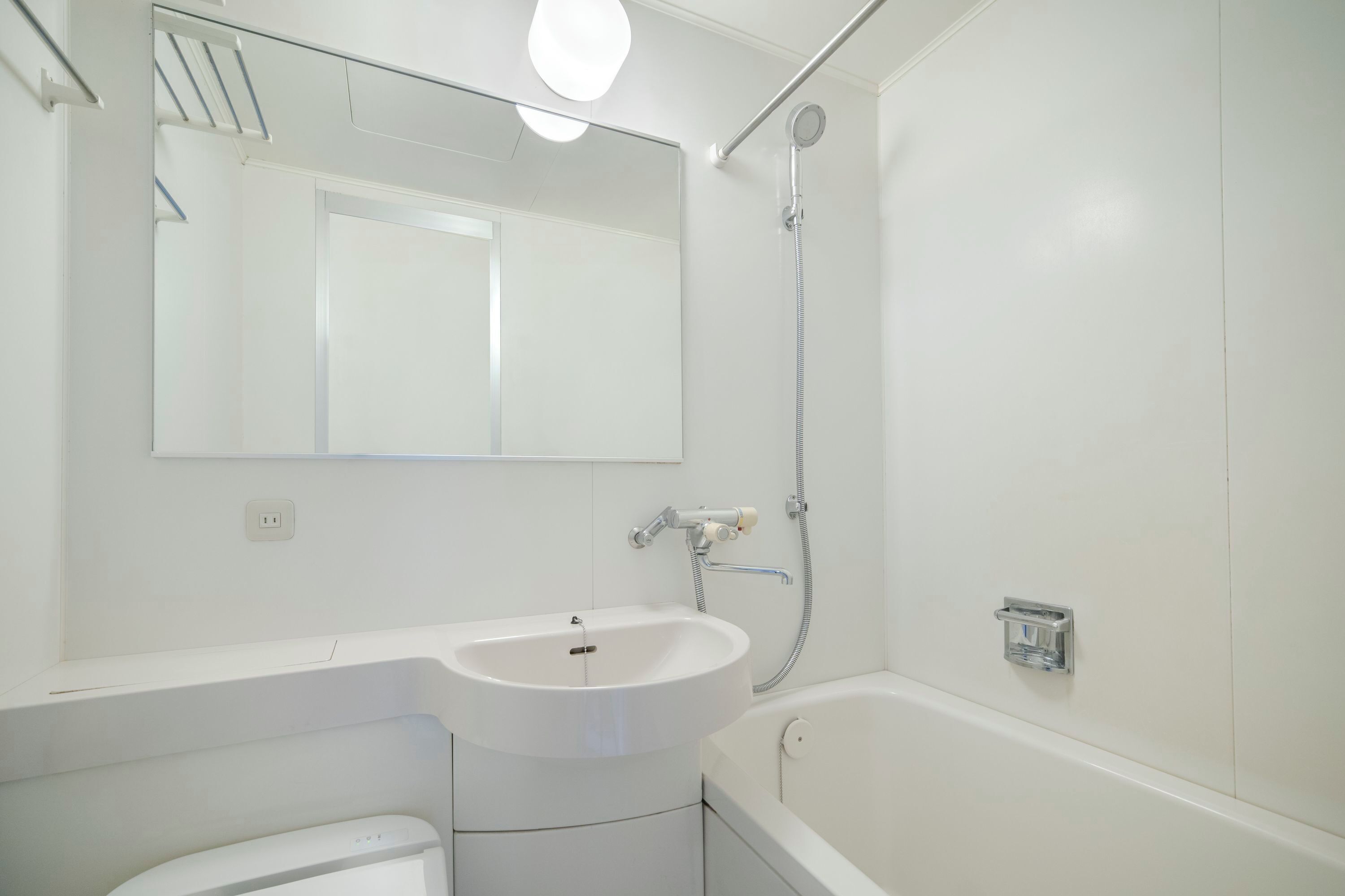 A bathroom with a sink, mirror, shower, and toilet.