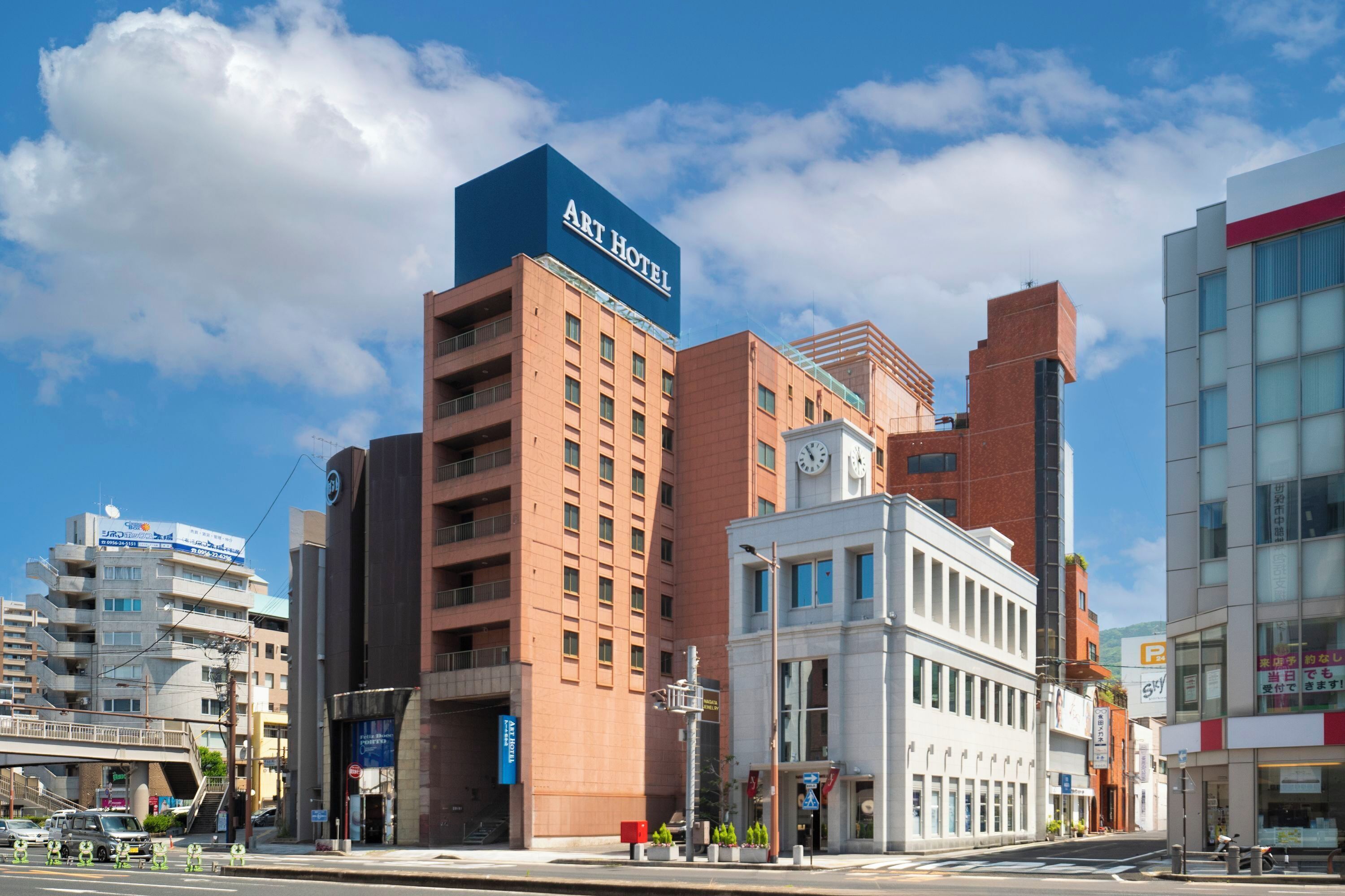 Un hotel con un llamativo cartel del Hotel Art, una torre del reloj y un edificio moderno con grandes ventanales.