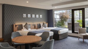 A hotel room with a large bed, two bedside tables, a round table, and two chairs. - ART HOTEL Sasebo Central (Sasebo)