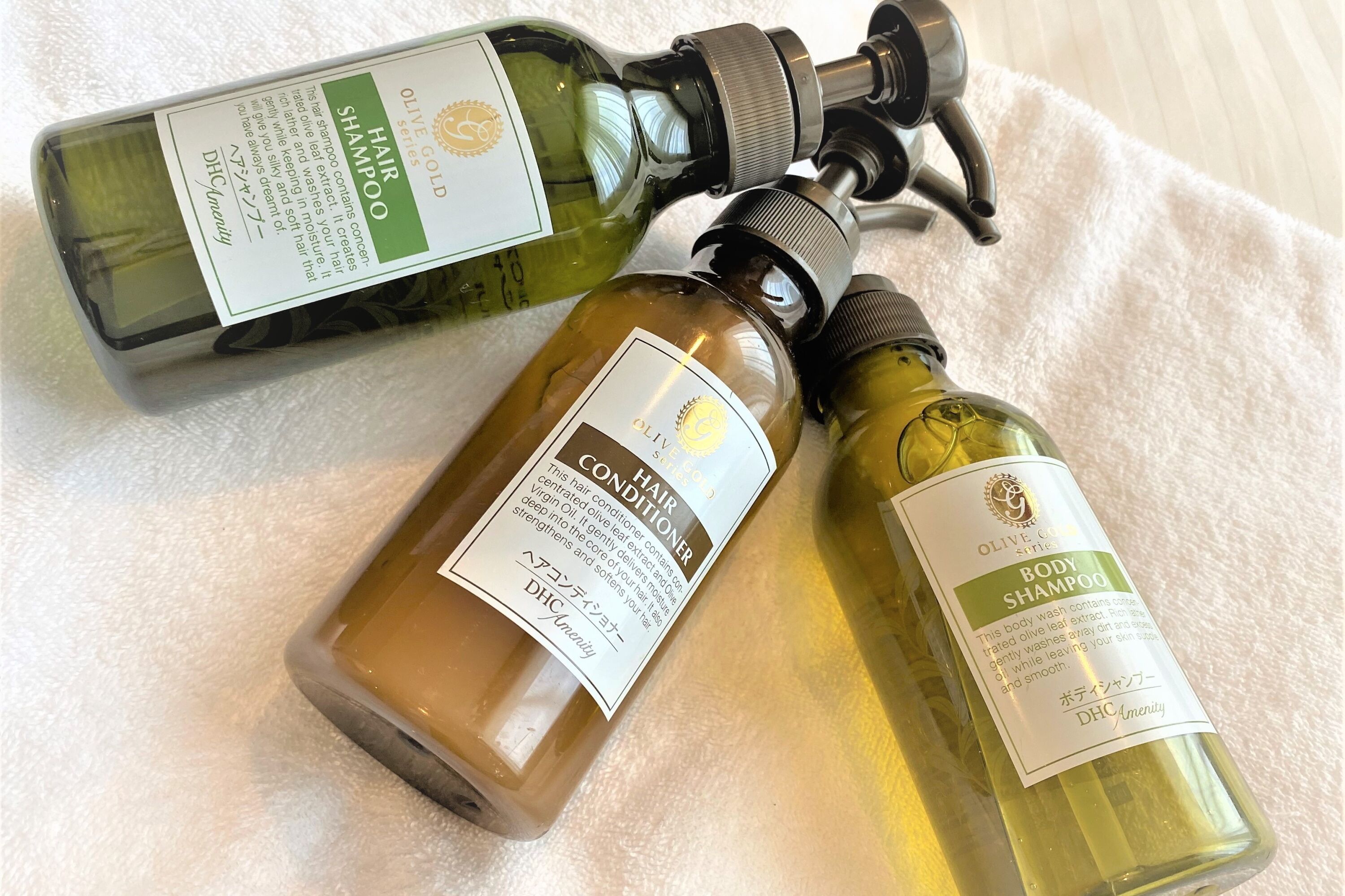 Three bottles of hair care products on a white towel.