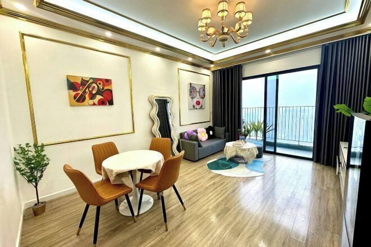 A modern living room with a dining area, a sofa, a chandelier, and a view of the outdoors.