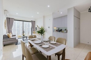 A modern living room with a dining area, a sofa, and a kitchen in the background.