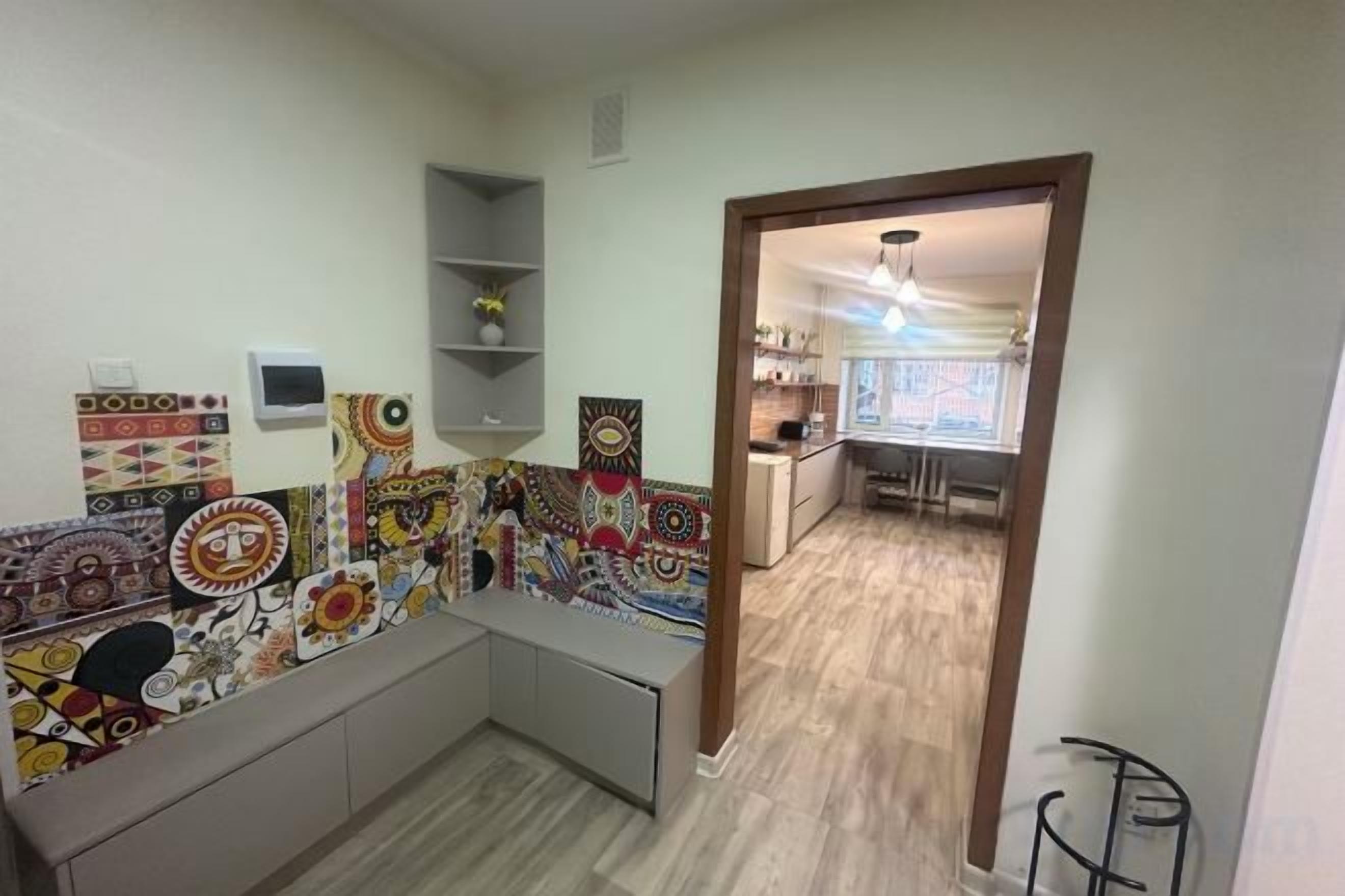 A room with a kitchen area, a dining table, and a built-in bench.