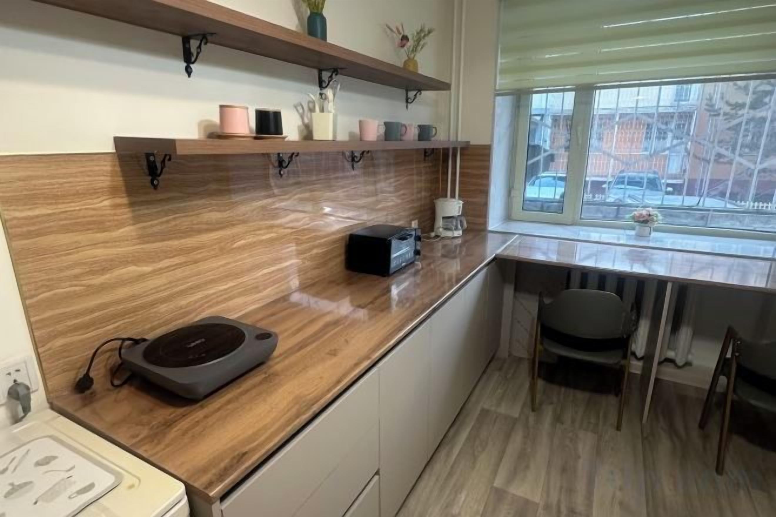 A kitchen with a wooden countertop, a coffee machine, and a window with a view of the outside.
