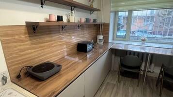 A kitchen with a wooden countertop, a coffee machine, and a window with a view of the outside.