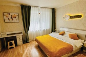 A bedroom with a bed, a desk, a chair, a nightstand, and a wall-mounted lamp. - Ray apartment (Ulaanbaatar)
