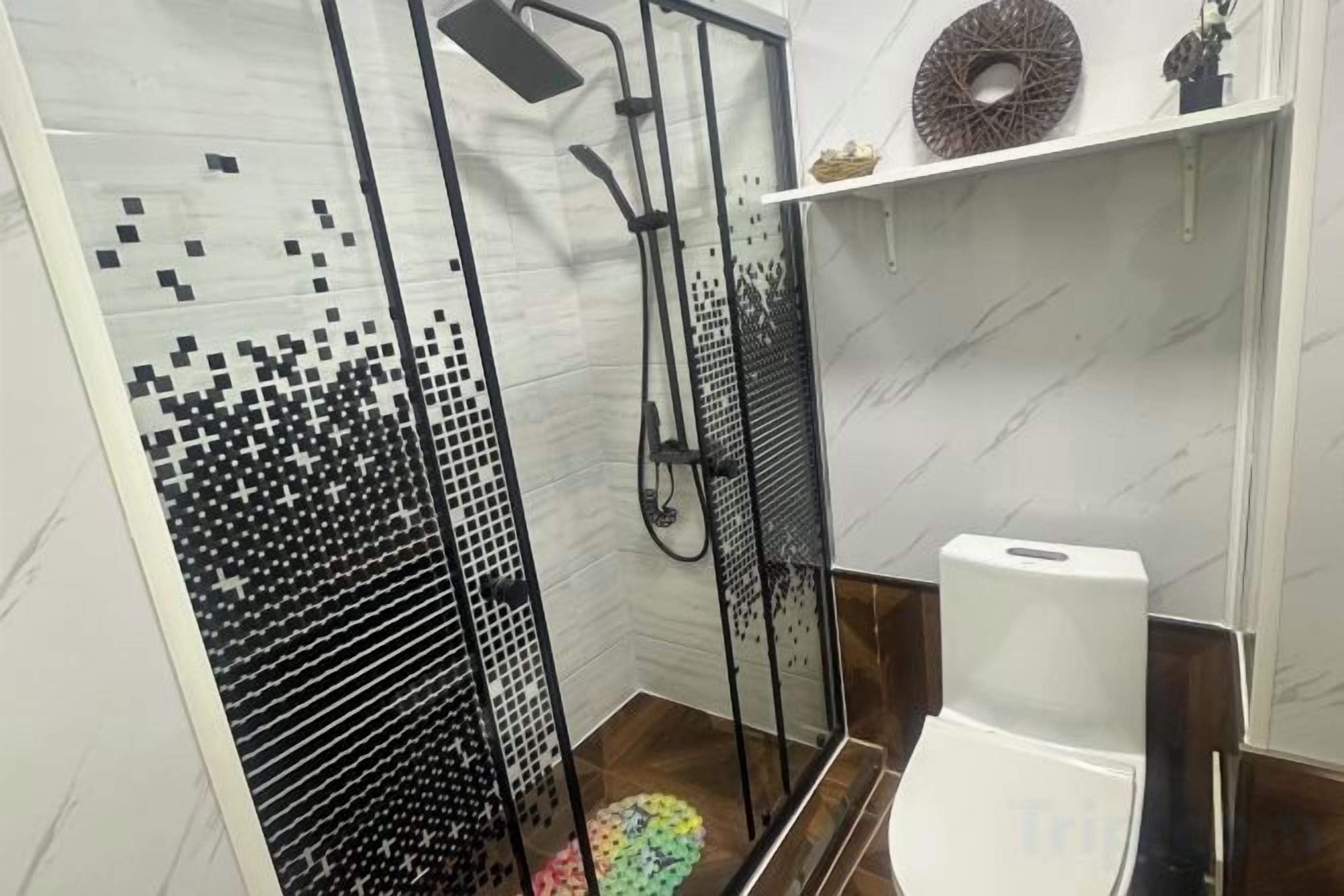 Ein Badezimmer mit Dusche, Toilette und Fliesen.