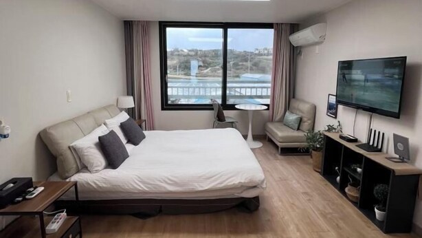 Una camera d'albergo moderna con un letto grande, una televisione, una scrivania e vista sull'esterno.