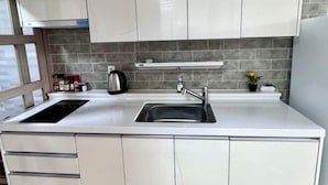 Una cucina moderna con mobili bianchi, un lavello in acciaio inossidabile e una cappa aspirante integrata.