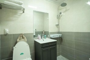 A bathroom with a toilet, sink, mirror, and shower. - Stay in JEJU (Jeju)