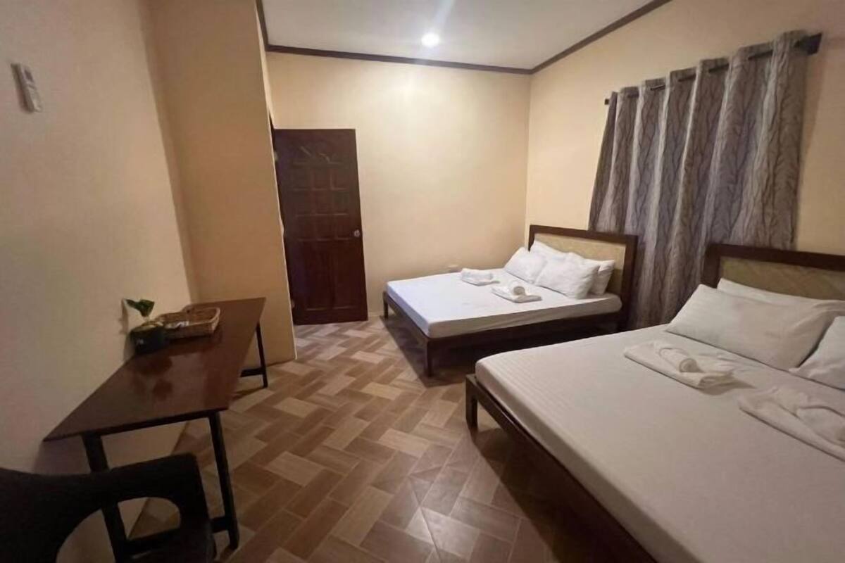 A hotel room with two beds, a wooden desk, and a small table.