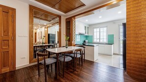 Una cocina moderna con una isla central, piso de madera y un comedor con mesa y sillas.