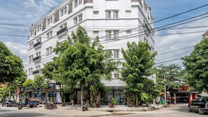 Un edificio de varios pisos con fachada blanca, balcones y una entrada en esquina.
