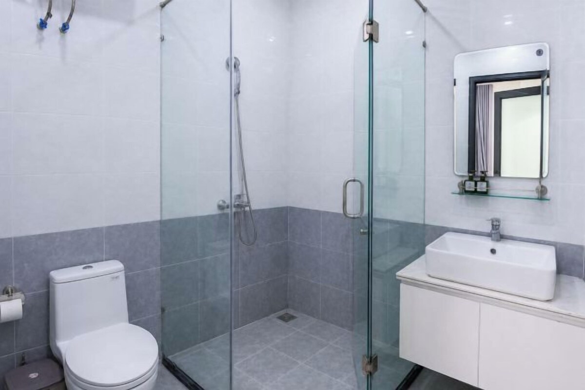 A bathroom with a glass-enclosed shower, a toilet, and a sink with a mirror above it.