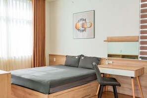 A bedroom with a bed, a desk, and a chair. - Merci Vinhomes Marina Hai Phong (Haiphong)