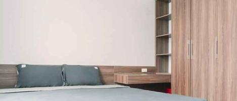 A bedroom with a bed, a wardrobe, and a shelf unit.