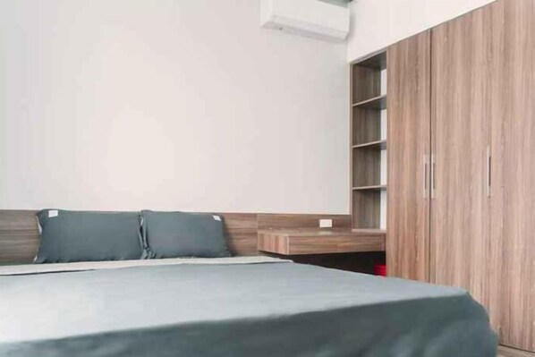 A bedroom with a bed, a wardrobe, and a shelf unit. - Merci Vinhomes Marina Hai Phong (Haiphong)