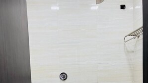 A small, clean bathroom with a white toilet, a dark door, and tiled walls. - Hotel Rourkela Palace (Rourkela)
