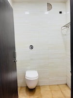 Un baño pequeño y limpio con inodoro blanco, una puerta oscura y paredes de azulejos.