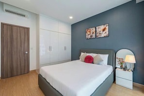Une chambre à coucher comprenant un lit, une table de chevet, une armoire et deux œuvres d’art accrochées au mur.