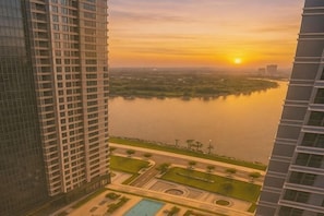 A high-rise building with a view of a body of water and a sunset.