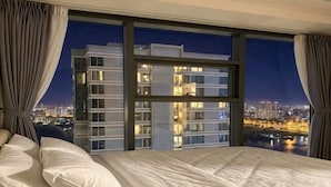 A hotel room with a large bed, a view of a cityscape, and a window with curtains. - An Corner - Sunwah Pearl Apartment (Ho Chi Minh City)