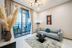 A modern living room with a sofa, a coffee table, and a large window with curtains. - An Corner - Sunwah Pearl Apartment (Ho Chi Minh City)