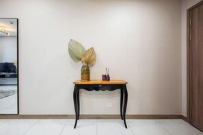 Une pièce avec une table en bois adossée à un mur uni, un miroir et une porte.