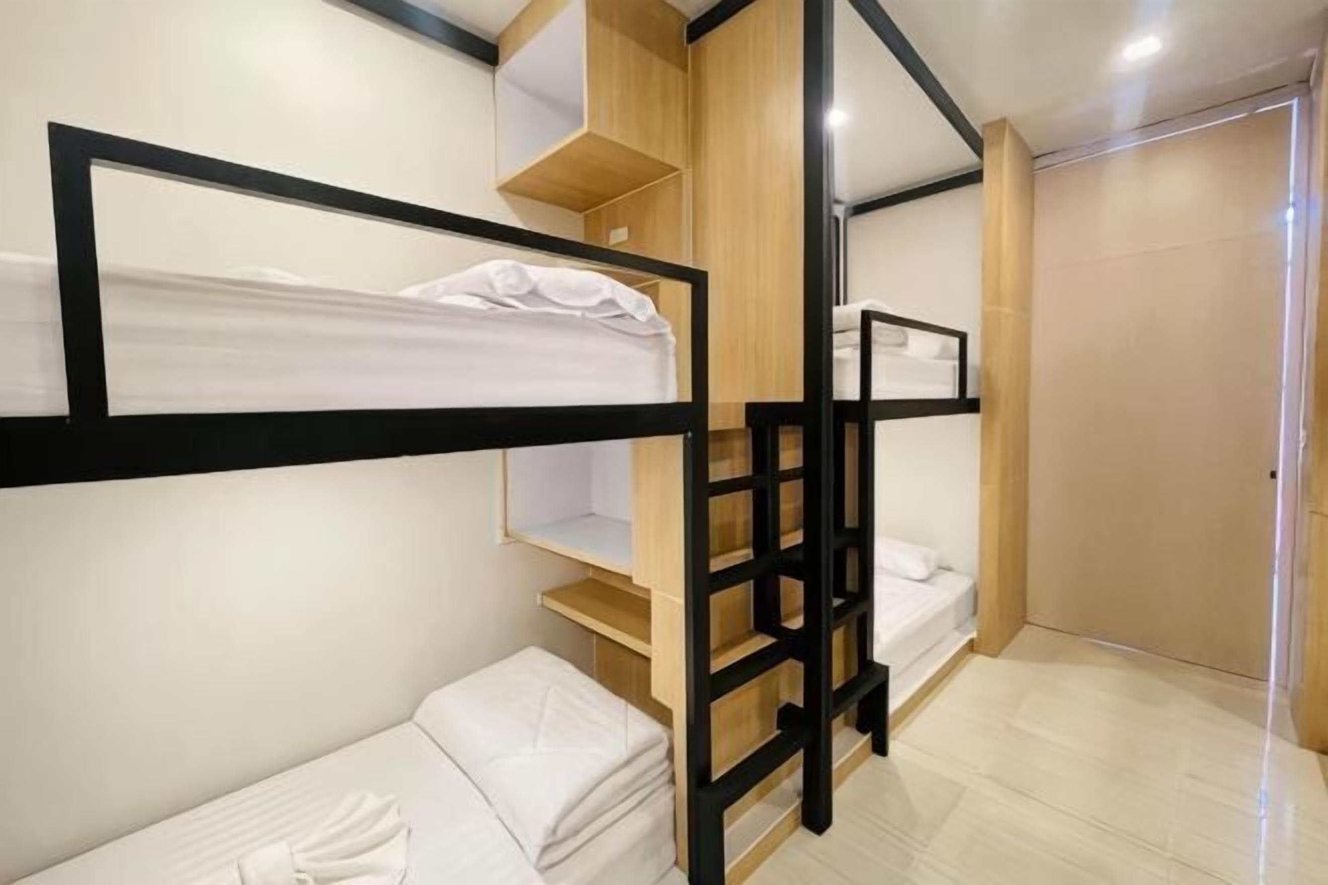 A compact room with bunk beds, a wooden wardrobe, and a door.