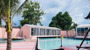 A swimming pool area with a pool, a palm tree, and a building with large windows.