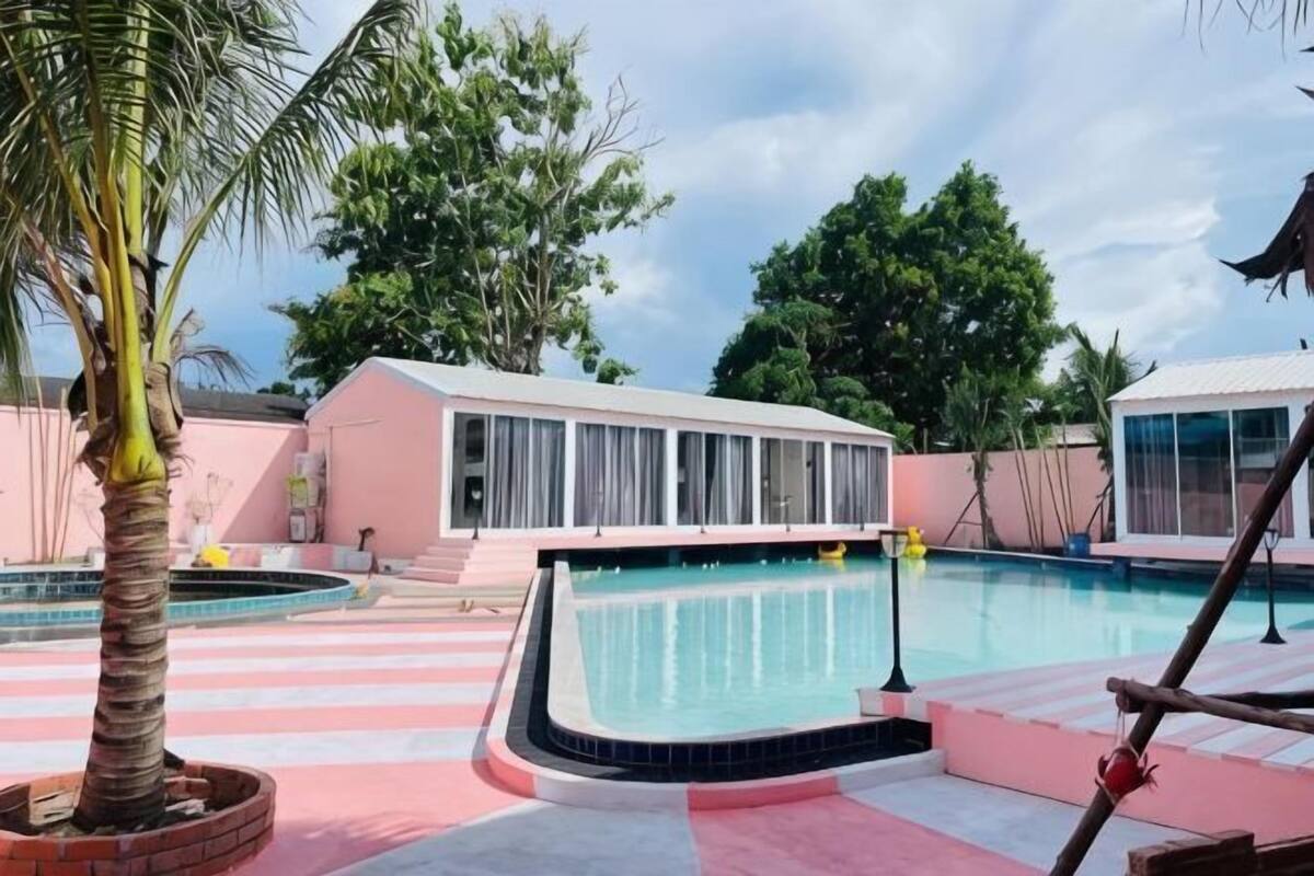 A swimming pool area with a pool, a palm tree, and a building with large windows.