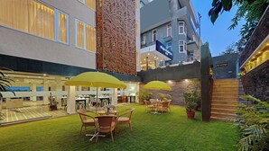 A hotel courtyard with outdoor seating, a decorative wall, and a sign for 'Ohaja Residences'. - Ahuja Residency GCR (Gurugram)