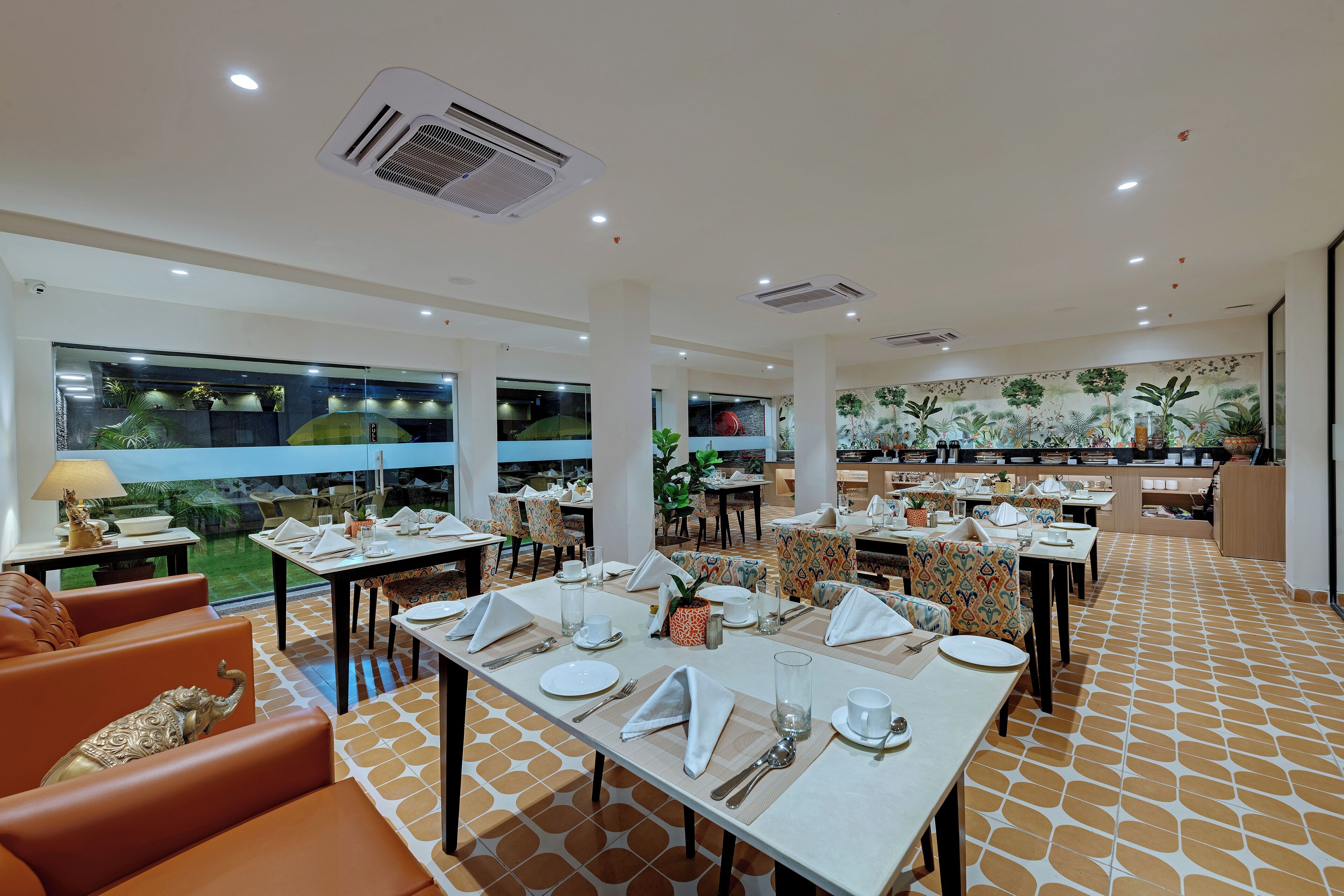 Un comedor amplio con varias mesas dispuestas para comer, rodeado de asientos cómodos y grandes ventanas que ofrecen vistas al exterior.