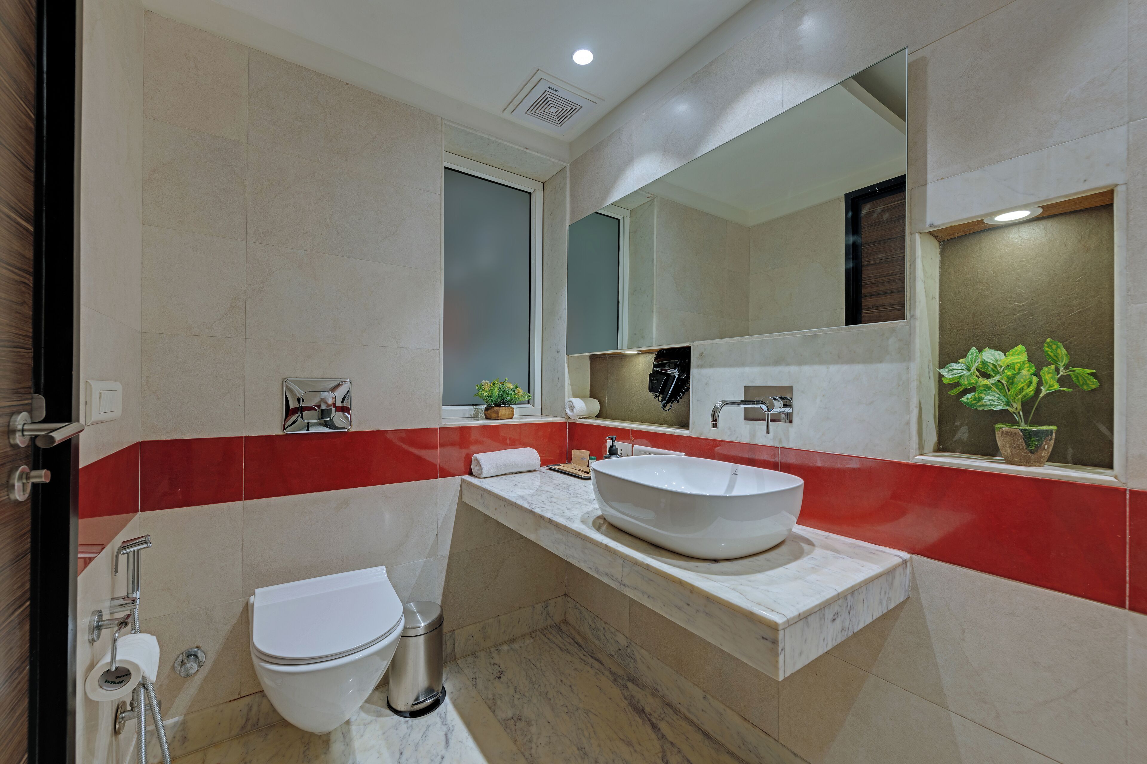 A modern bathroom with a white sink, a toilet, and a mirror above the sink.
