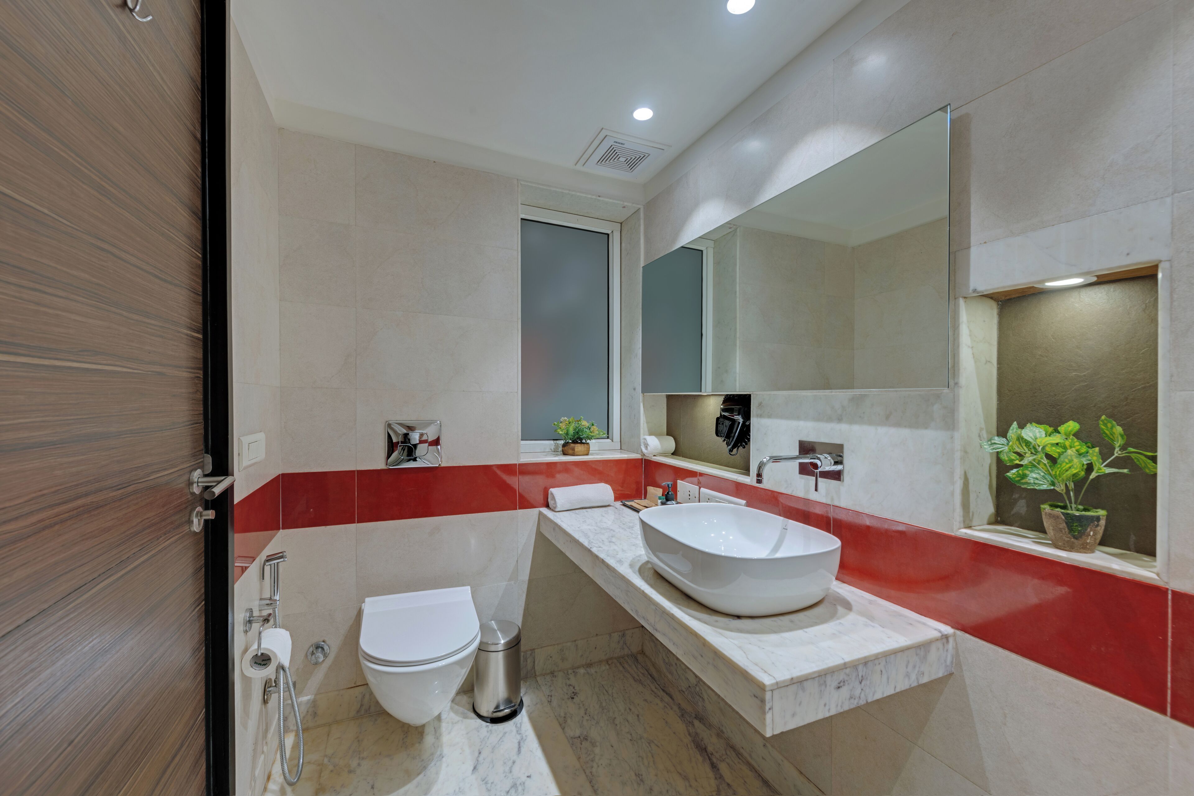 A modern bathroom with a white toilet, a large white sink, and a mirror above the sink.