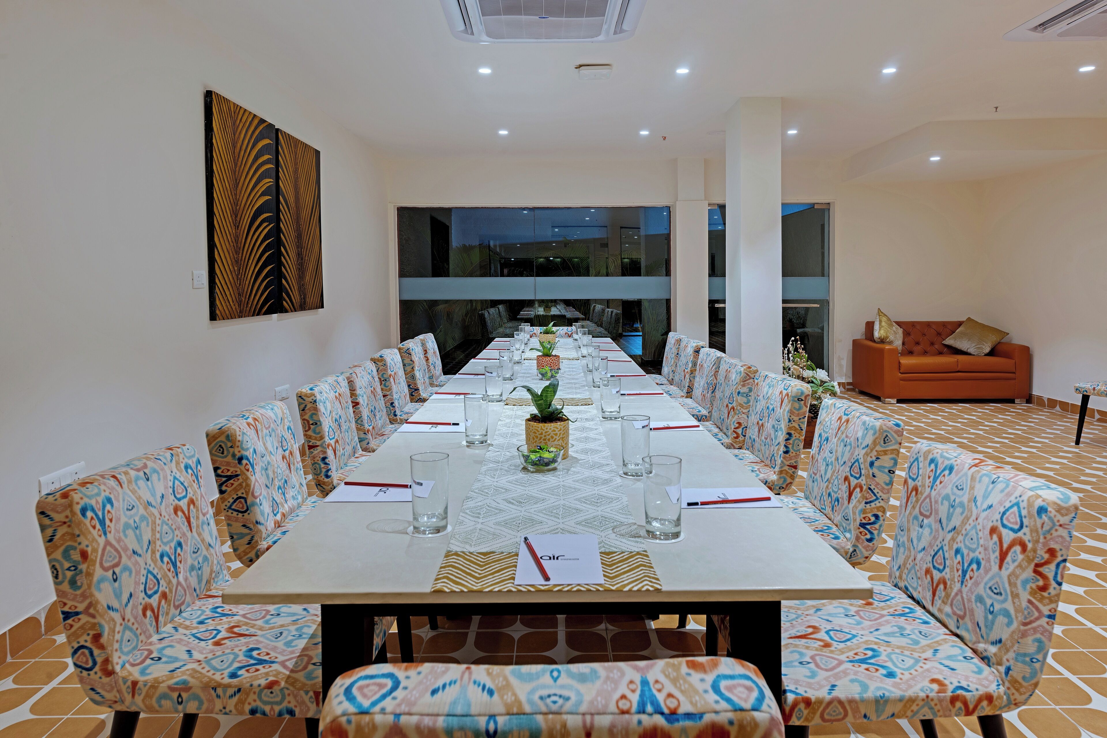 Un salón de conferencias con una larga mesa, sillas estampadas y un amplio ventanal.