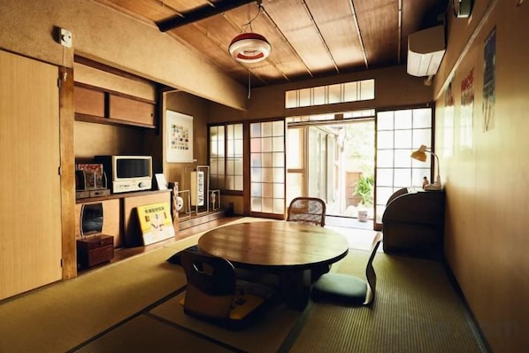 A traditional Japanese-style room with tatami flooring, a round table, and sliding doors. - BORO-YA (Osaka)