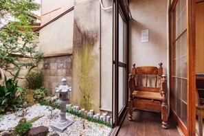 Una entrada tradicional al estilo japonés con un banco de madera, un farol de piedra y un pequeño jardín.