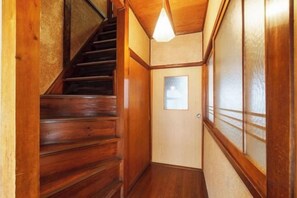 Una escalera de madera que lleva a una habitación con una ventana y una puerta.