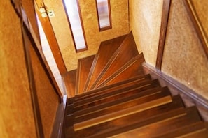 Una escalera de madera con barandilla y un muro alfombrado.