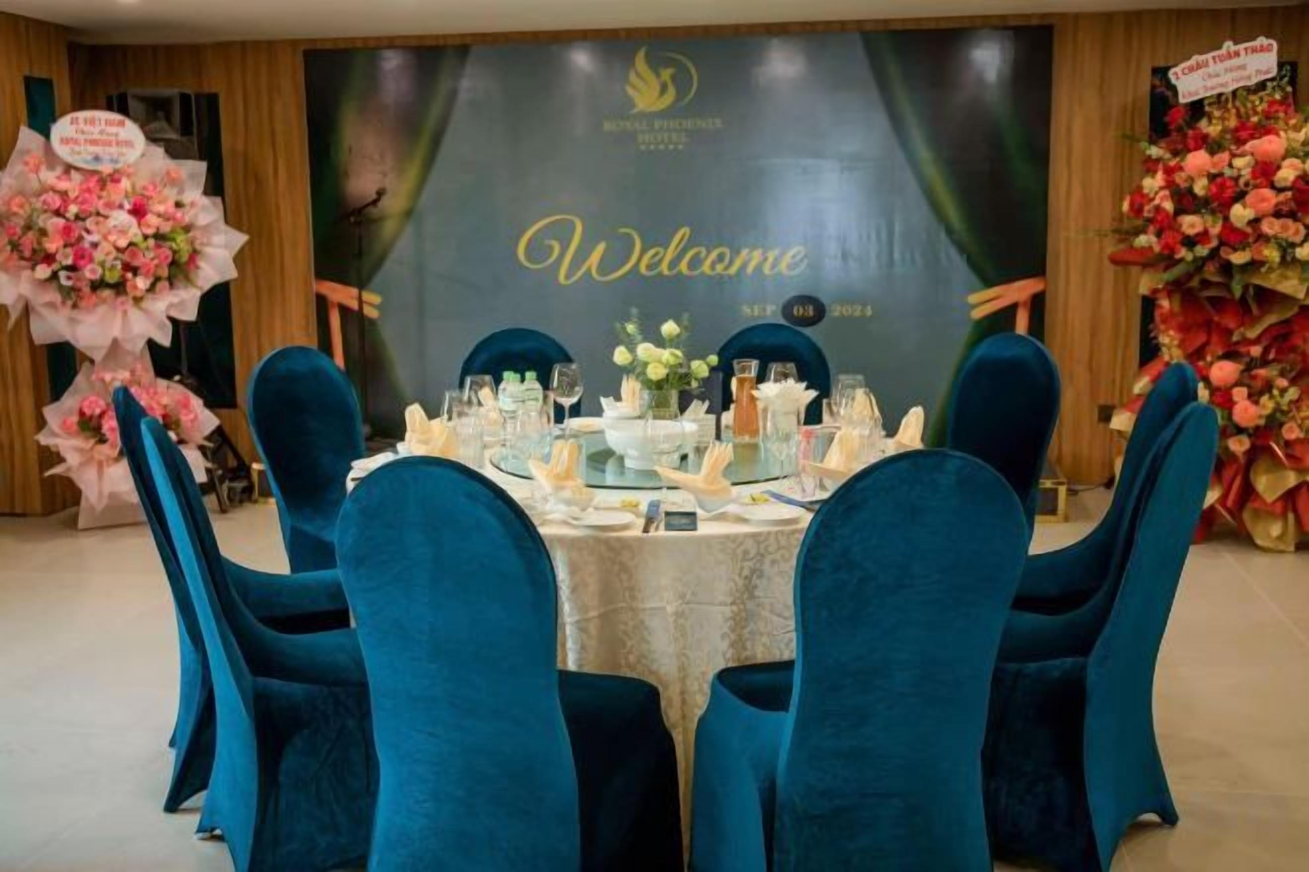 A formal dining setup with a round table, blue chairs, and floral decorations.