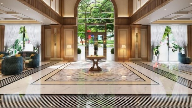 Un hall d’entrée spacieux, doté d’une grande porte en arc de cercle, d’une table centrale et d’un motif à carreaux sur le sol.